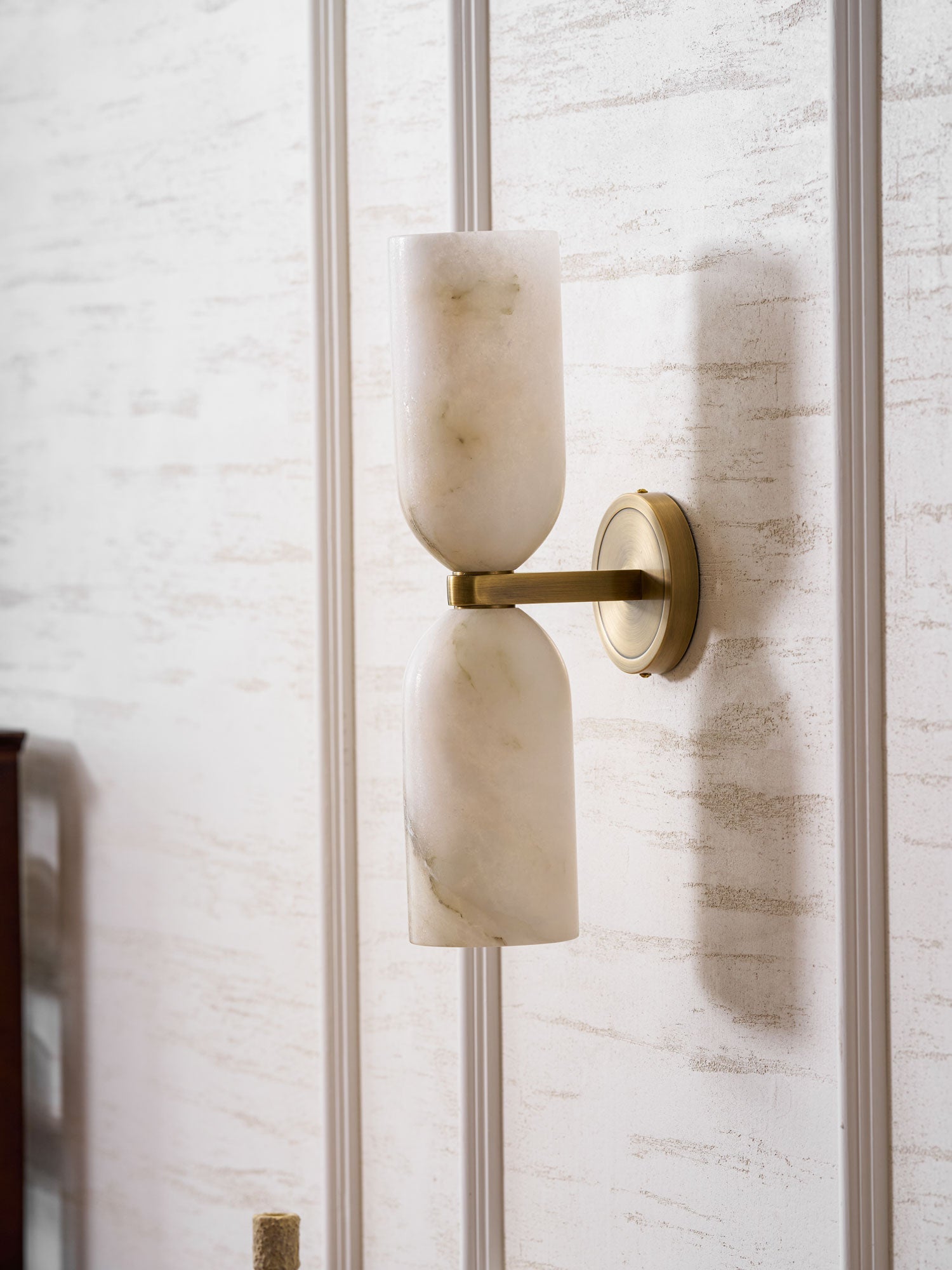 Alabaster wall sconce with copper finish glowing in a room