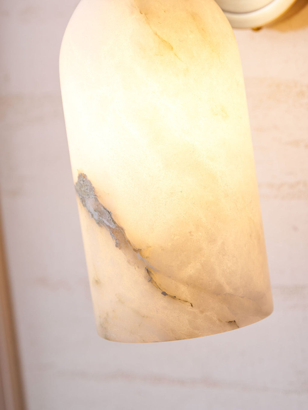 Lit lower shade of the Nexus Modern Alabaster Wall Light, with a grey mineral vein glowing through.