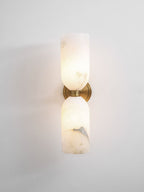 Nexus Modern Alabaster Wall Light lit against a pale grey wall, both stone shades glowing warm from within.