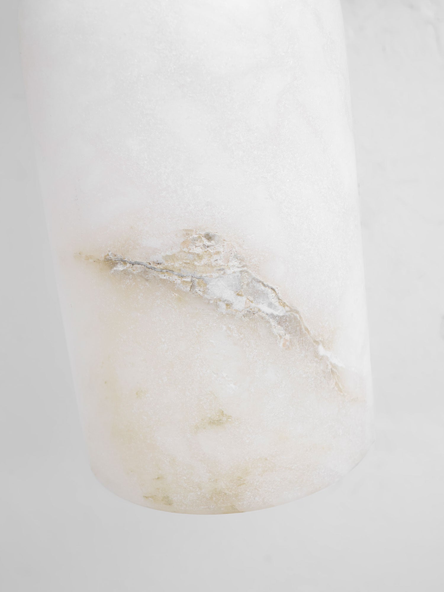 Macro of the alabaster shade on the Nexus wall light, showing the crystalline grain and mineral seam.