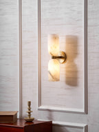 Angled view of the lit Nexus Modern Alabaster Wall Light, its warm glow washing the panelled wall behind.