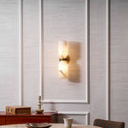 Wide view of the lit Nexus Modern Alabaster Wall Light above a dining table in a panelled room.