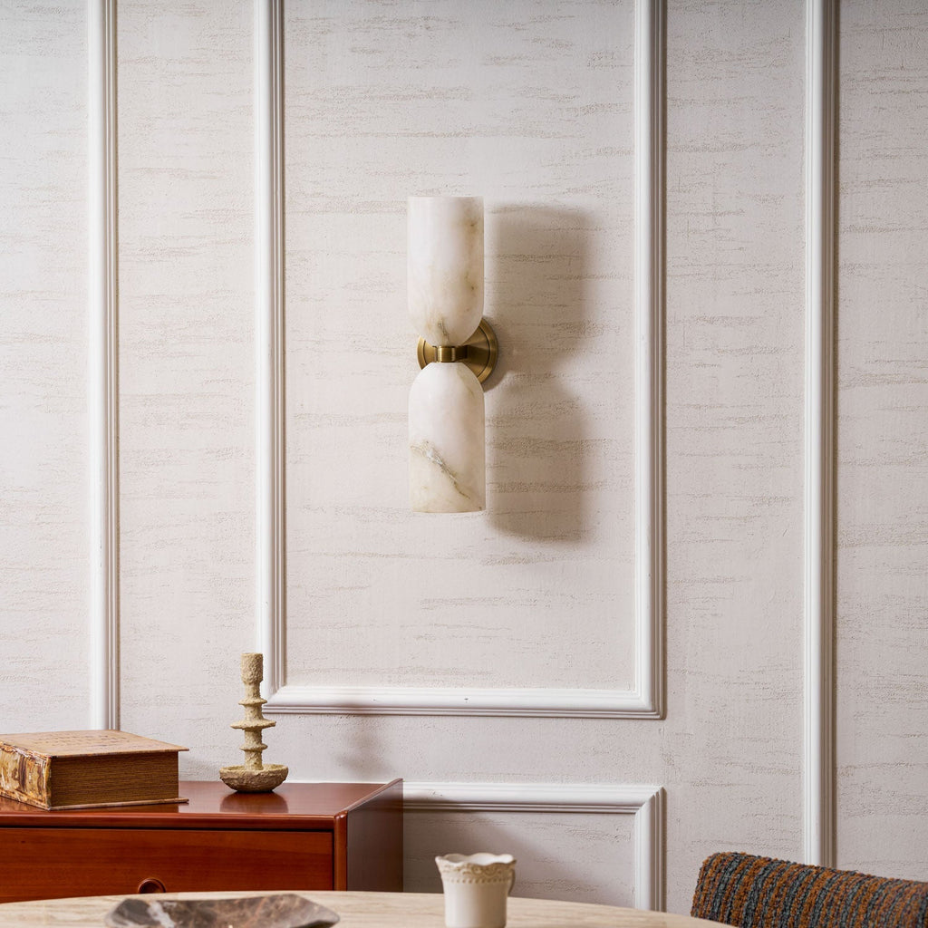 The unlit Nexus Modern Alabaster Wall Light on a panelled wall, stone veining visible in daylight.