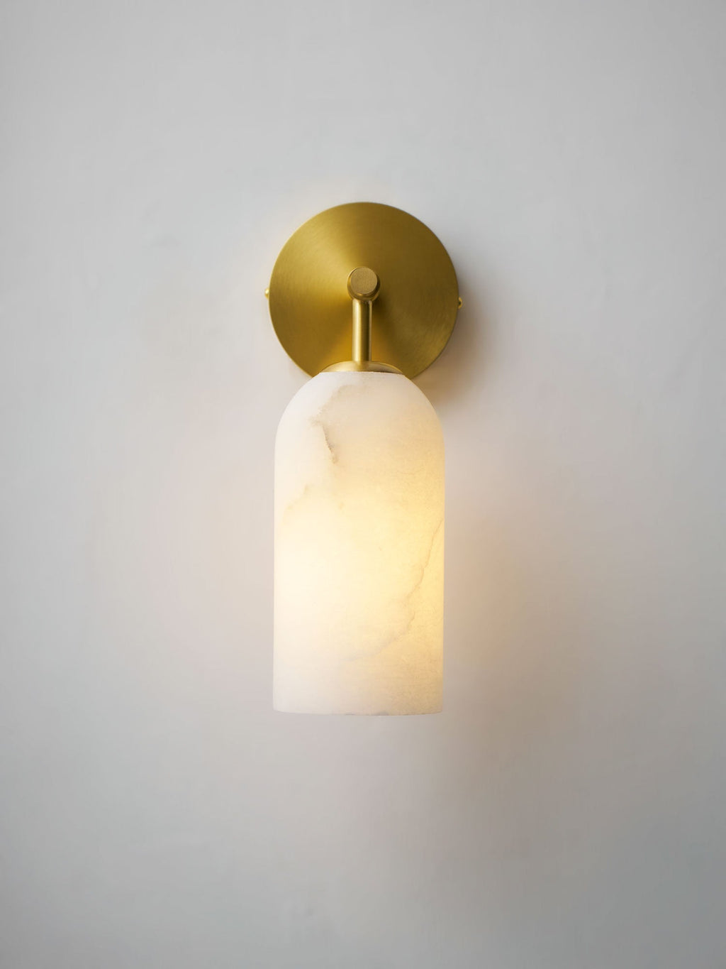 Alabaster pillar wall light in gold and white with warm glow