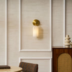 Alabaster wall light with gold arm casting a soft ambient glow