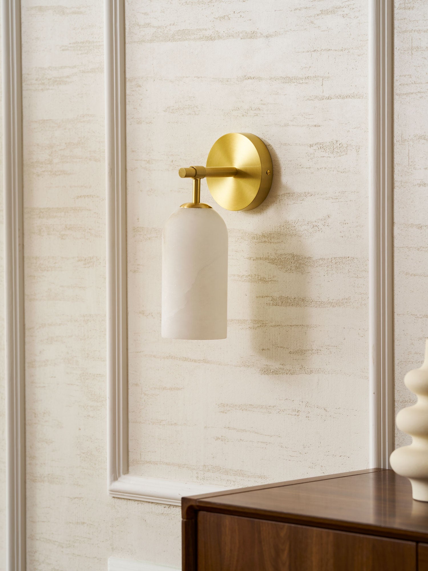 White alabaster wall sconce casting soft warm light in a room