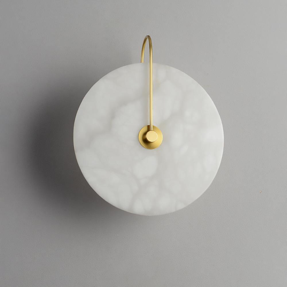 Unlit gold-arm Elaris wall light on grey, the pebbled translucency of the alabaster clearly visible.