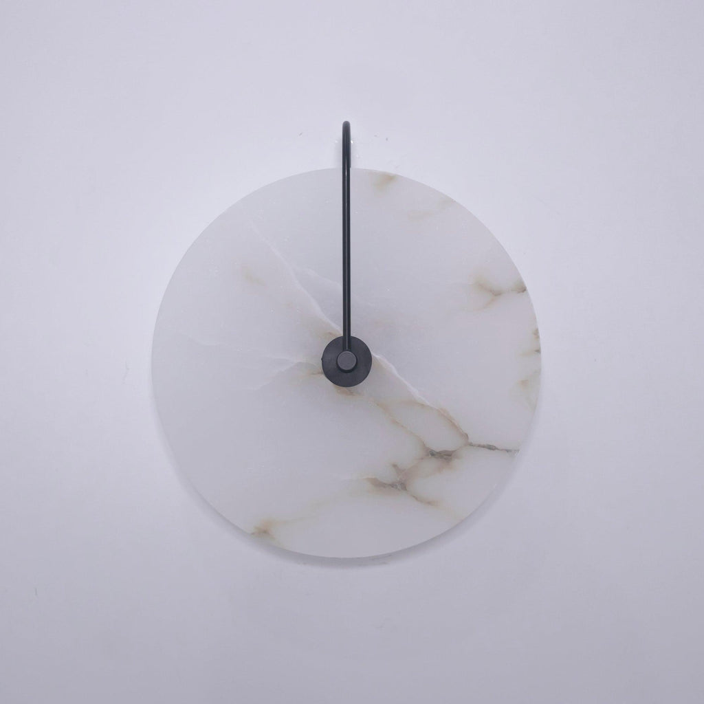 Unlit Elaris wall light with a black arm, the alabaster disc showing golden-brown veins.