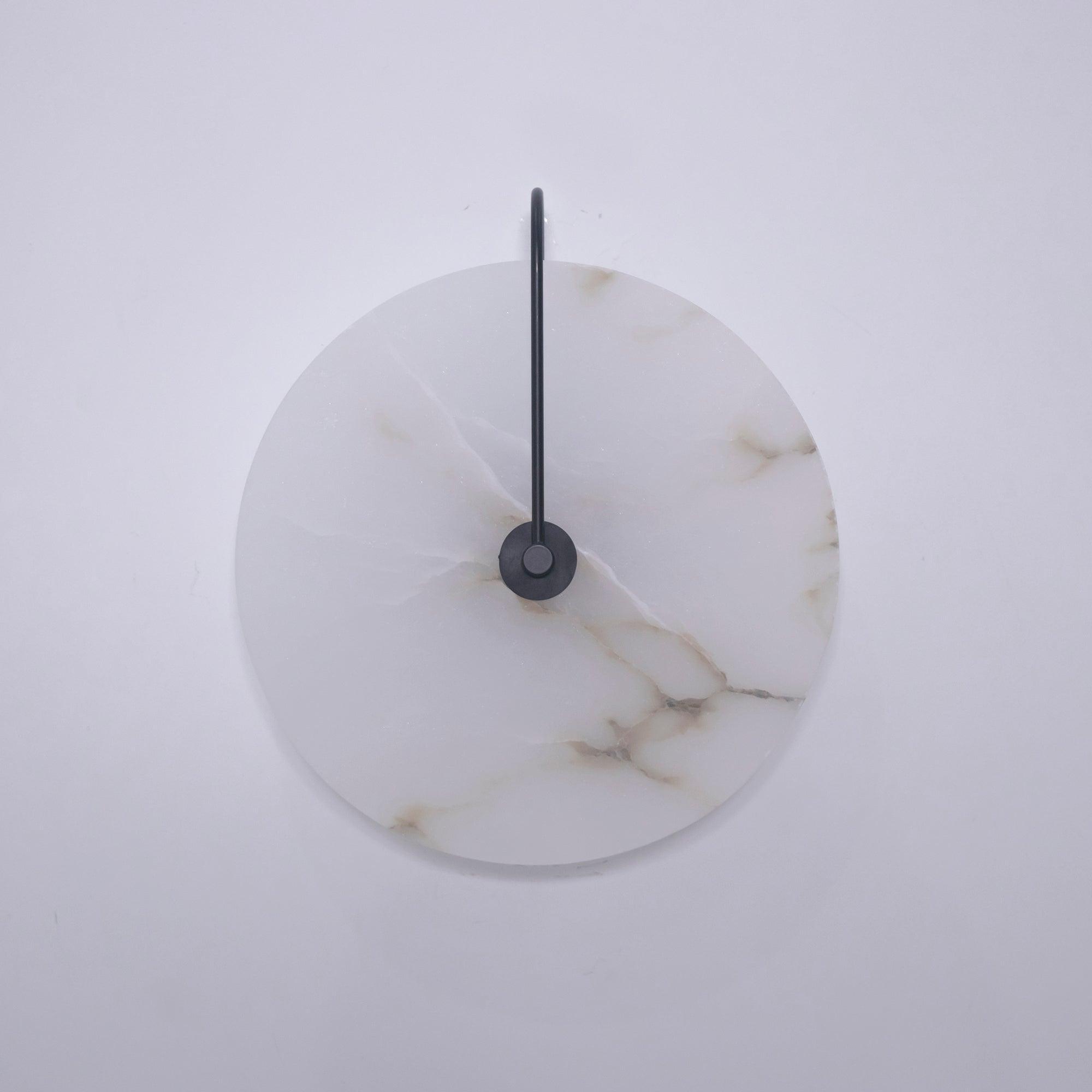 Unlit Elaris wall light with a black arm, the alabaster disc showing golden-brown veins.
