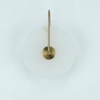 Unlit Elaris wall light in antique brass, close view of the arched arm and round centre mount.