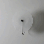 Unlit Elaris wall light in black, straight-on view showing the matte alabaster disc and hook arm.