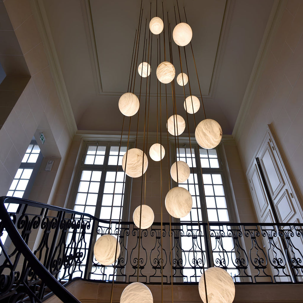 Looking up at the cluster in a classical stairwell with tall windows and an iron balustrade.