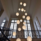 Looking up at the cluster in a classical stairwell with tall windows and an iron balustrade.