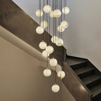 Alabaster ball cluster hanging beside a dark marble staircase, spheres glowing softly.