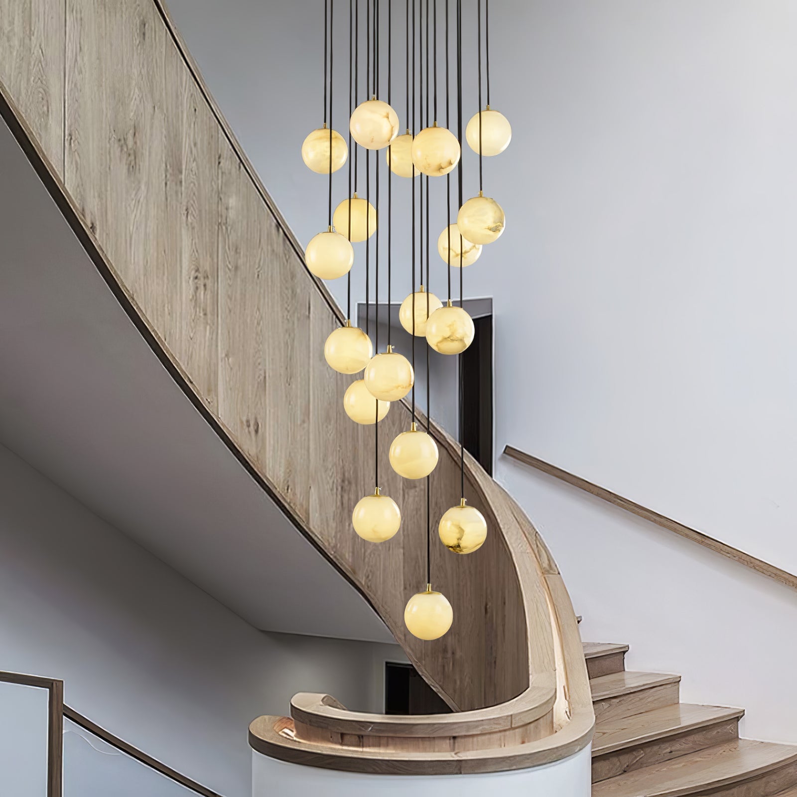 Afralia alabaster cluster chandelier lit above a curved oak staircase, balls glowing warm.
