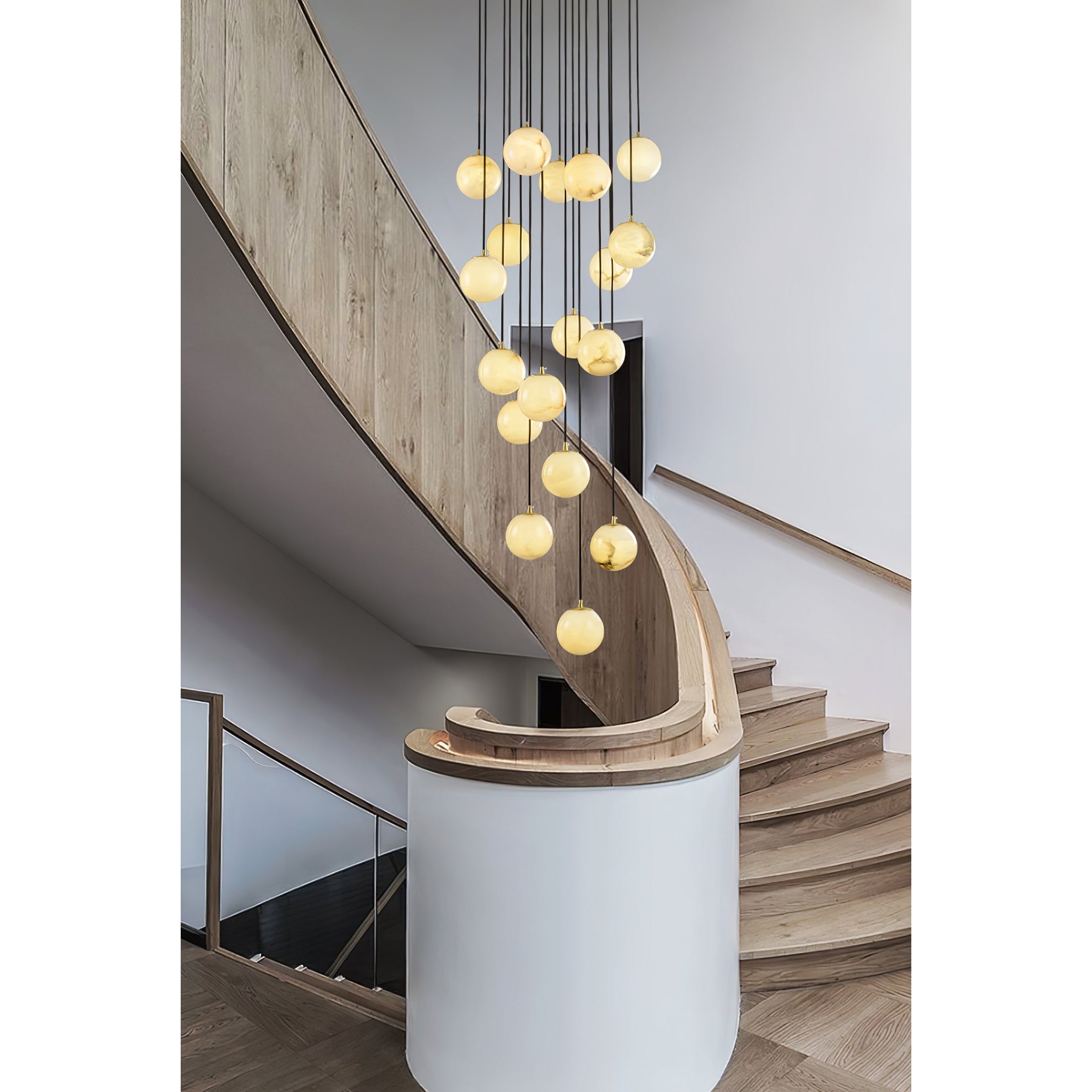 The cluster hung in the void of a pale oak curved staircase, each ball lit from within.