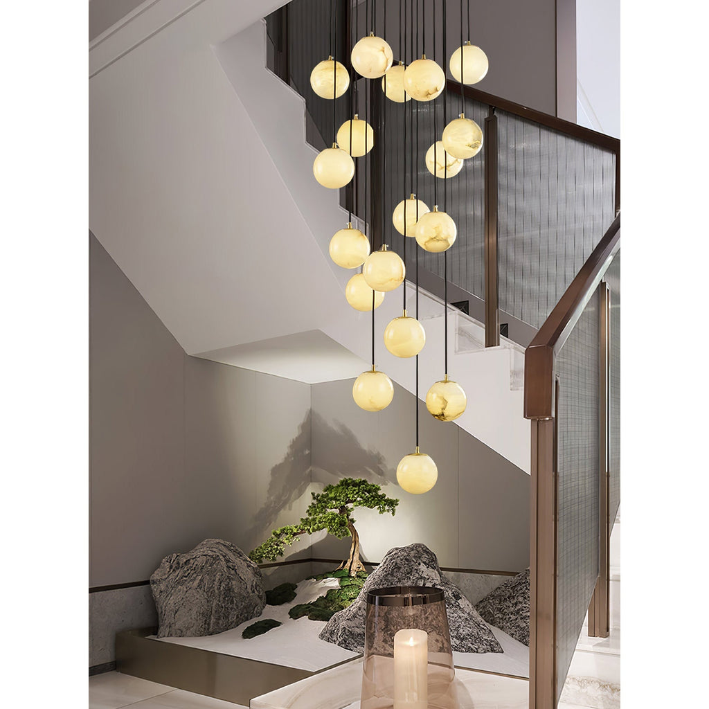 Tight view of the cascade in a bronze-railed stairwell, a candle lantern in the foreground.