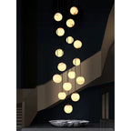 The cluster lit in a dark lobby above a veined marble bowl, balls reading as pale moons.