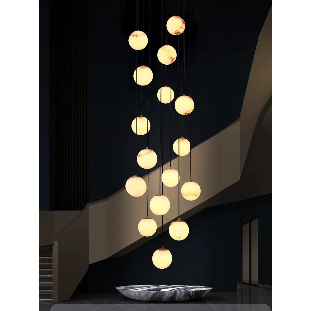 The cluster lit in a dark lobby above a veined marble bowl, balls reading as pale moons.