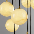 Close crop of several alabaster balls overlapping, brass fittings and black cords behind.