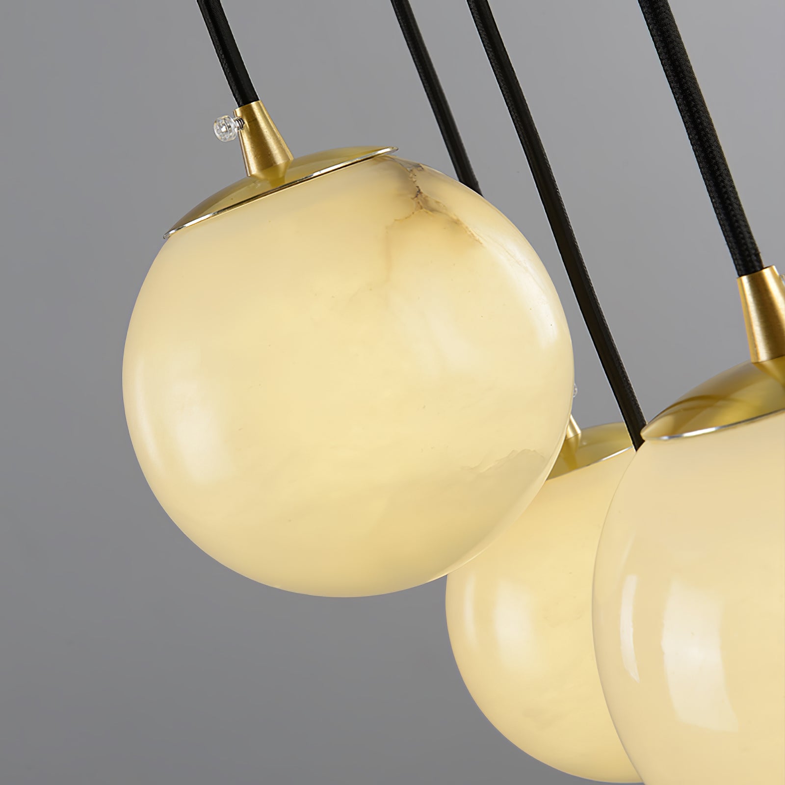 Close-up of one alabaster ball and its brushed brass cap, stone veining clearly visible.