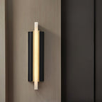 Angled shot of the lit Aurelian sconce on a warm wood-panelled wall beside a dark doorway