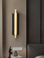The fixture lit on wood panelling beside a bed, sockets and a glass vase on the table below.