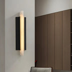 Wider room view of the Aurelian alabaster sconce lit on a white corner wall opposite wood cabinetry