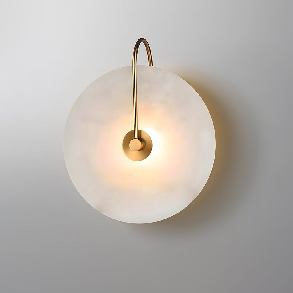 Lit gold Elaris wall light on grey, angled slightly to show the depth of the alabaster disc.