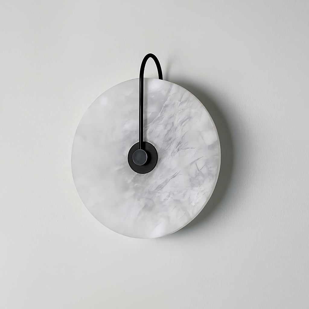 Kristy wall lamp unlit in the black-arm finish, grey marbled veining visible across the stone disc.