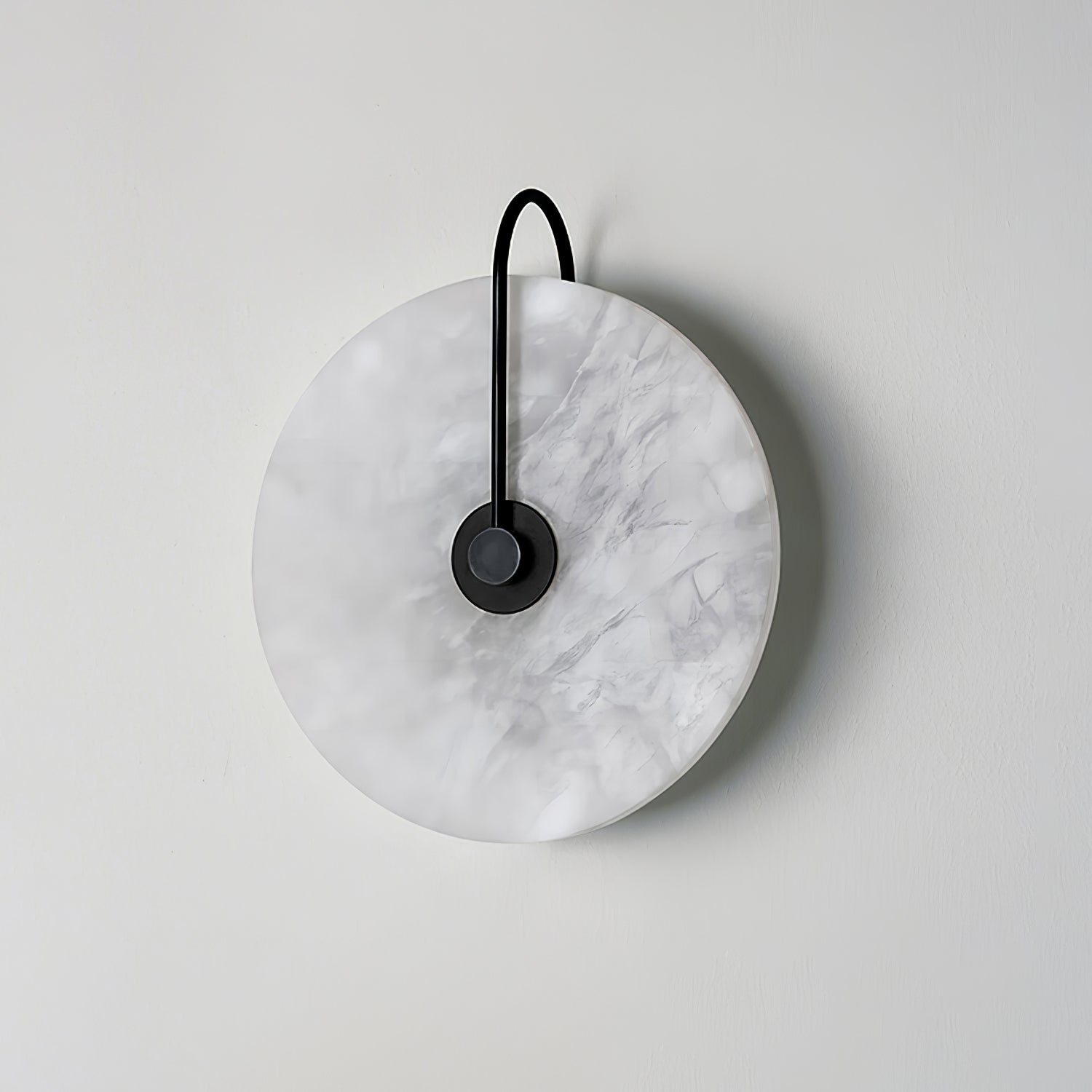 Unlit black-arm Elaris wall light on a white wall, grey cloud-like markings across the stone.