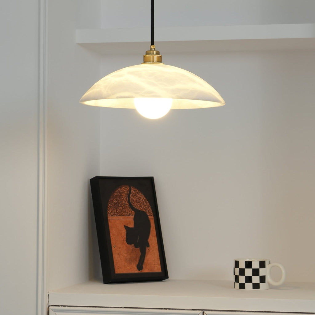 Nerea pendant lit in a white alcove, the bare bulb glowing beneath the veined stone shade.