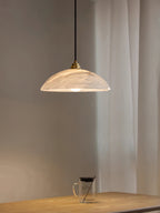 White alabaster pendant with brass fitting over a kitchen island