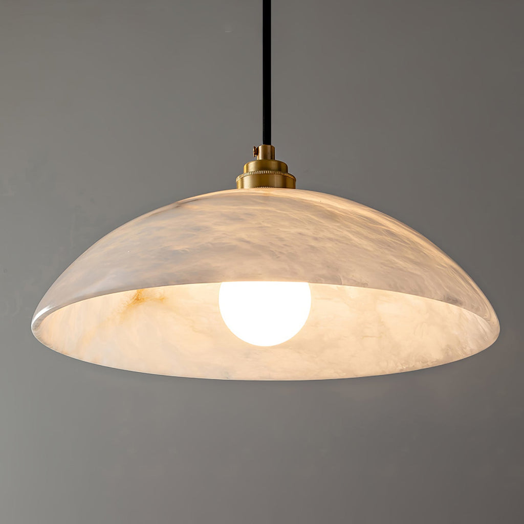Close-up under the Ritta pendant, showing the veined alabaster interior and its glowing globe bulb.