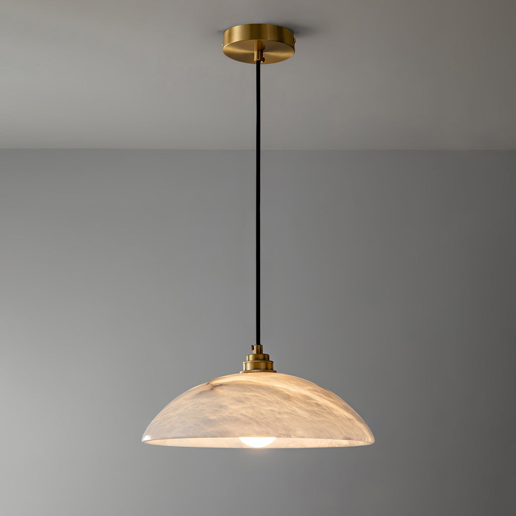 Ritta alabaster dome pendant shown at full drop with brass ceiling plate against a grey wall.