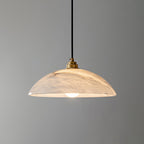 White alabaster pendant light glowing softly above a dining table