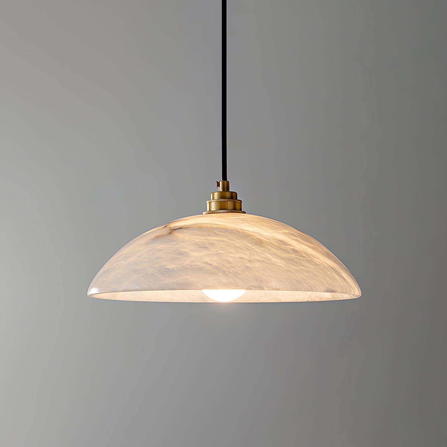 White alabaster pendant light glowing softly above a dining table