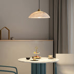 Nerea pendant hanging above a round marble cafe table set with a tiered dessert stand and teacup.
