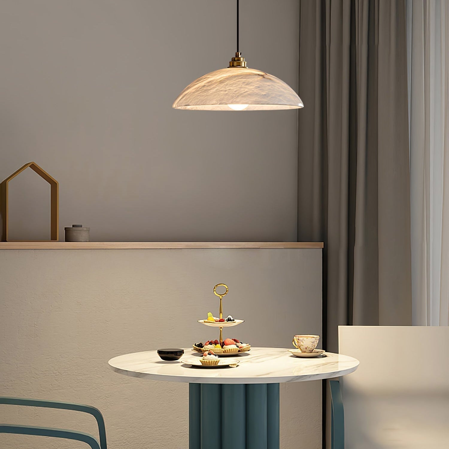 Nerea pendant hanging above a round marble cafe table set with a tiered dessert stand and teacup.