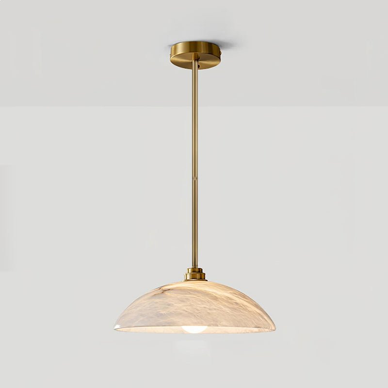 Alabaster dome pendant light with brass fitting glowing over a table