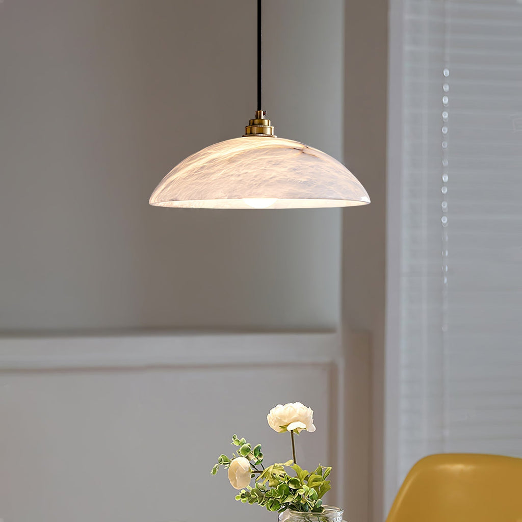 Nerea pendant lit at an angle above a dining table, the glow reflected inside the dome.
