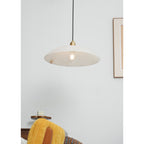 Nerea pendant lit above a bedroom chair, clear globe bulb visible under the pale stone dome.