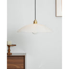 Unlit Nerea pendant over a walnut sideboard with a bubble candle on a small wooden stand.