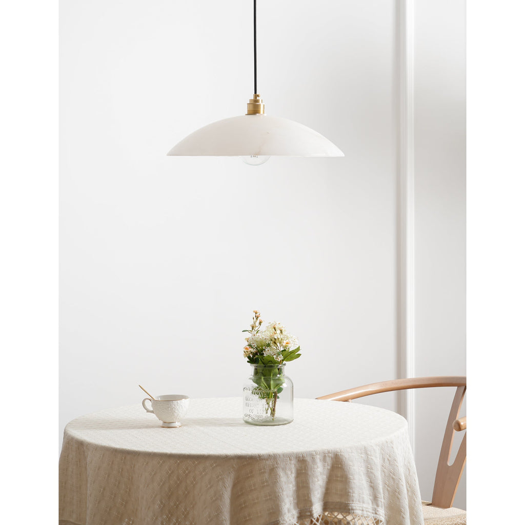 The unlit Nerea pendant over a round table dressed in cream linen, seen from further back.