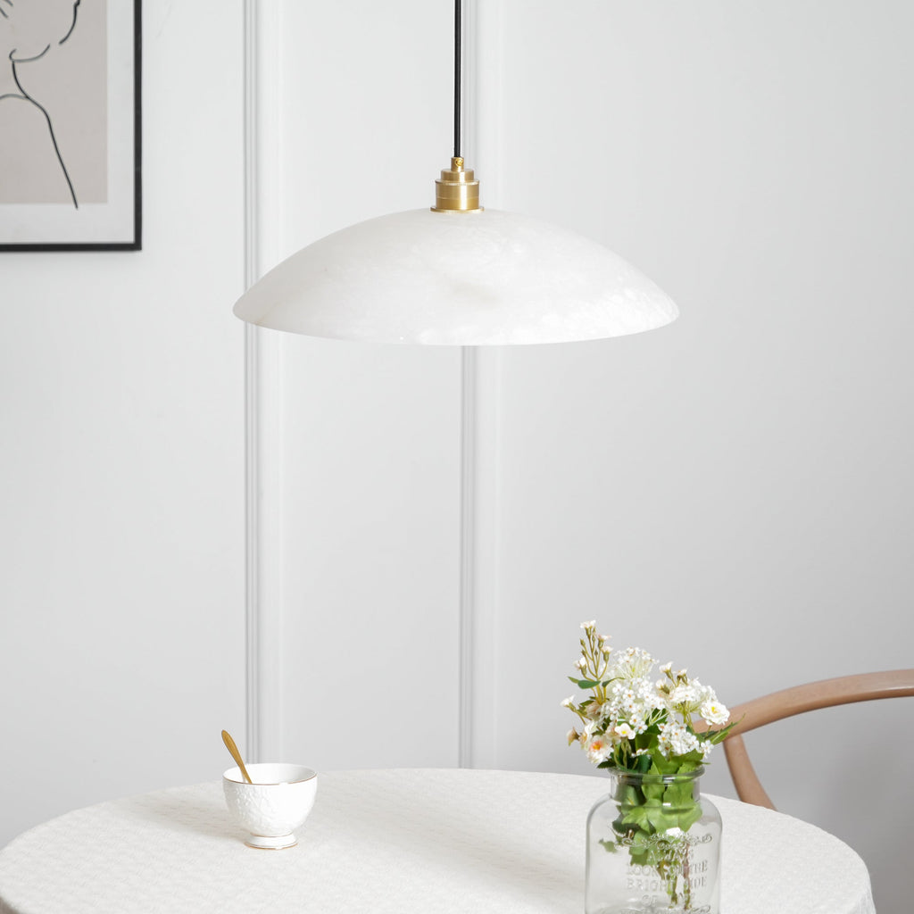Brass and alabaster dome pendant light glowing in a styled space