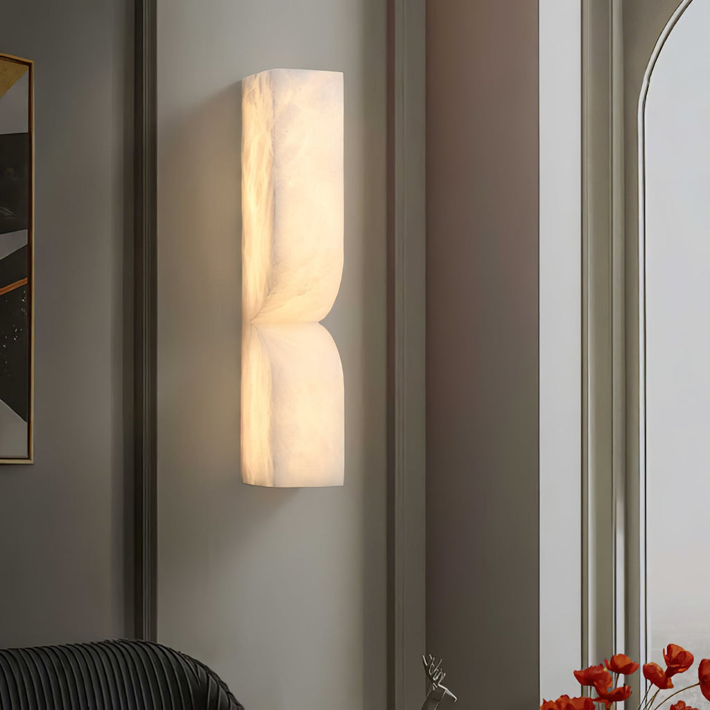 Solid stone alabaster sconce casting gentle light beside decor