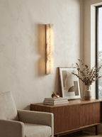 Sculptural alabaster wall light glowing softly above a console