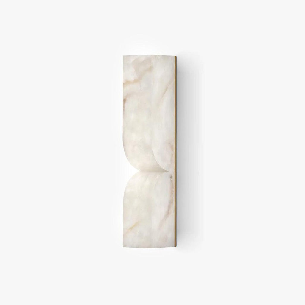Solid carved alabaster wall sconce glowing warmly on an interior wall