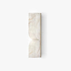 Solid carved alabaster wall sconce glowing warmly on an interior wall
