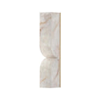Carved alabaster wall light with warm sculptural glow on the wall